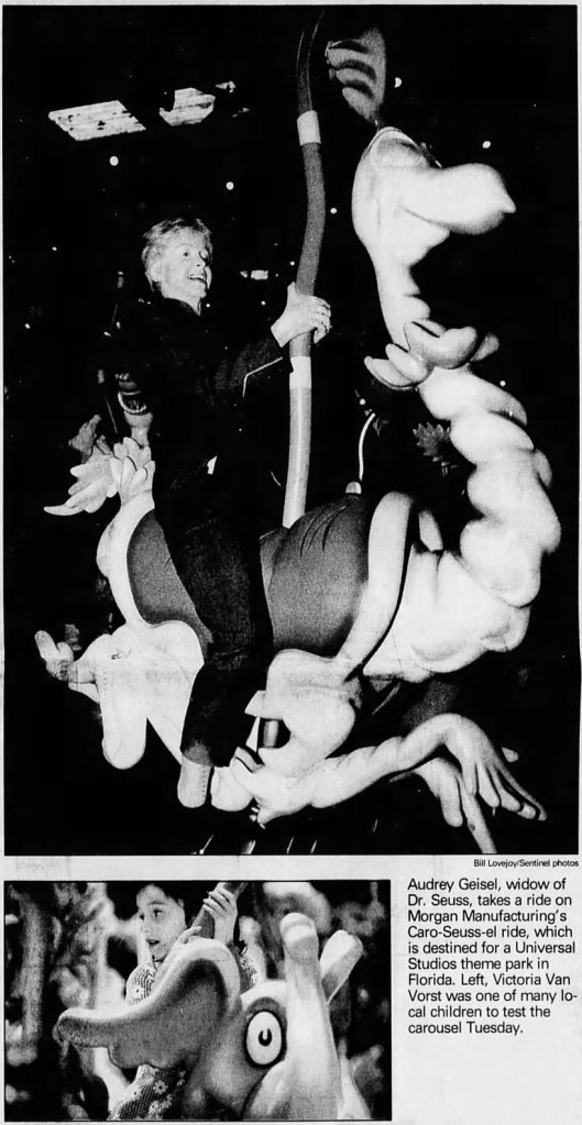 Audrey Geisel, widow of Dr. Seuss, riding the Caro-Seuss-el carousel designed by Morgan Manufacturing, with a child visible in the background enjoying the ride.